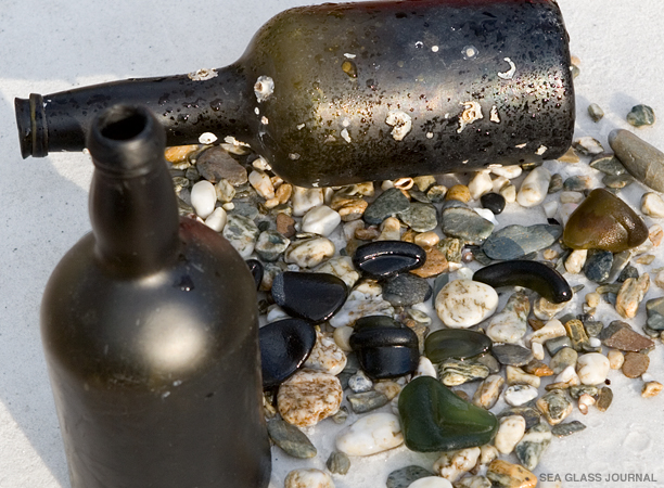 Black sea glass along with small stones and rocks.