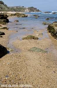 In the distance of this sea glass beach is San Cristobal Fort